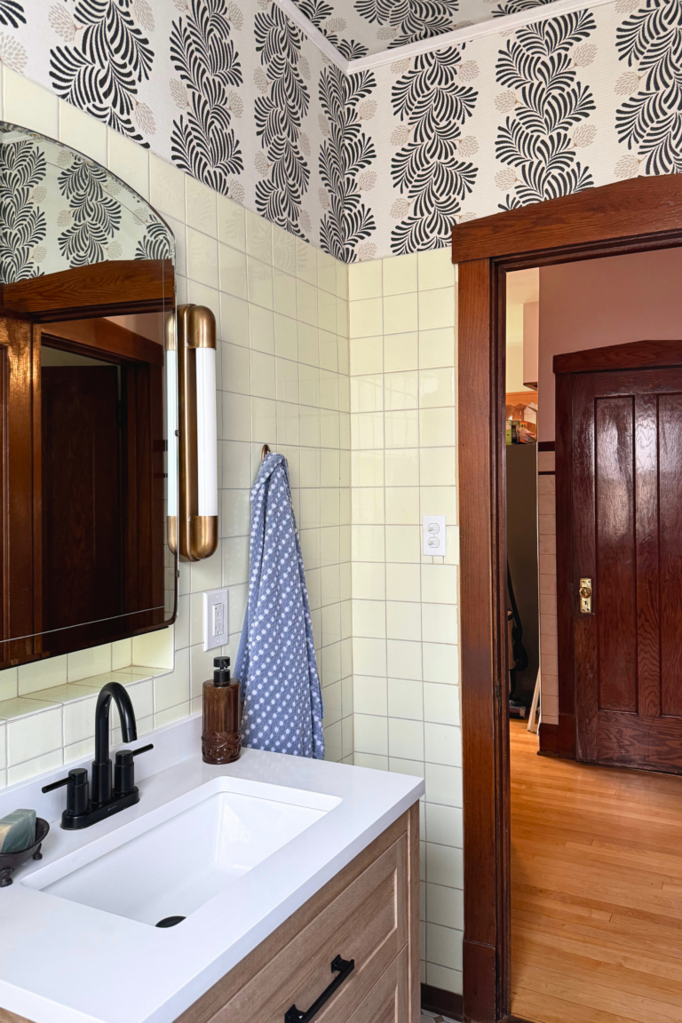 Custom oak bathroom vanity with white quartz countertop, black faucet, and vintage cream tile walls.